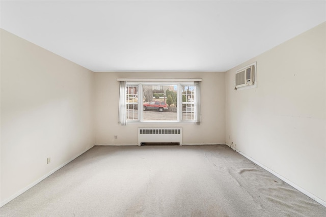 spare room with a wall unit AC, radiator, and light carpet