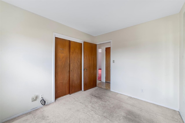 unfurnished bedroom with a closet and light colored carpet