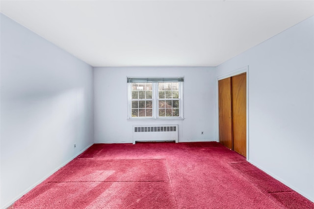 carpeted spare room featuring radiator heating unit