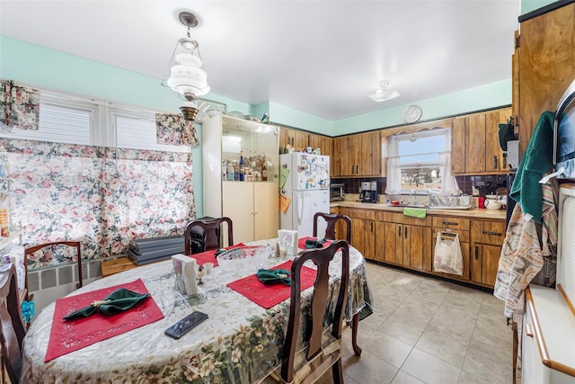 kitchen featuring backsplash, radiator, pendant lighting, white fridge, and light tile patterned flooring