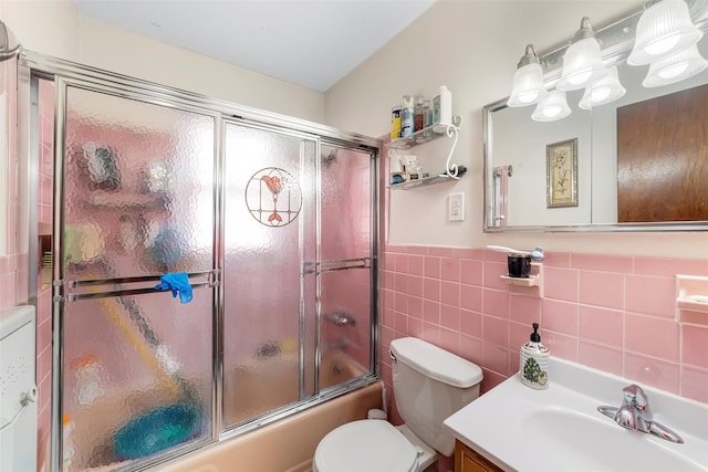 full bathroom featuring vanity, bath / shower combo with glass door, tile walls, and toilet