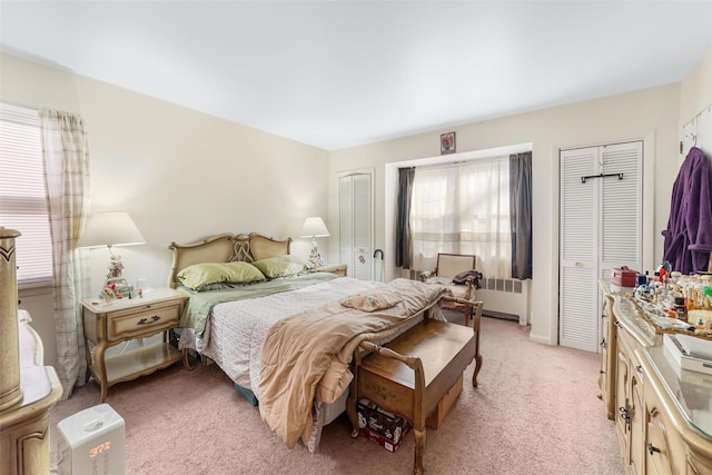 carpeted bedroom with multiple closets and radiator heating unit