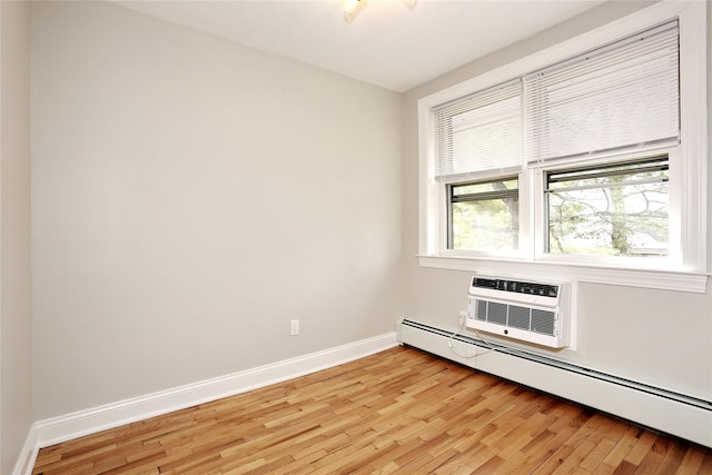 spare room featuring an AC wall unit, a baseboard radiator, and light wood-type flooring