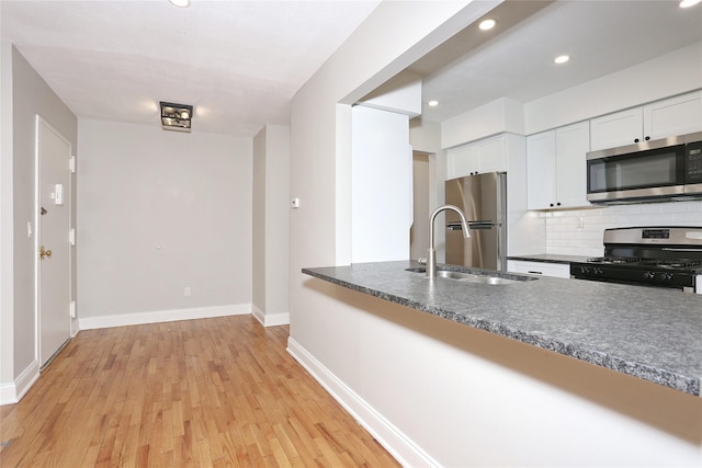 kitchen with backsplash, white cabinets, sink, light hardwood / wood-style flooring, and stainless steel appliances