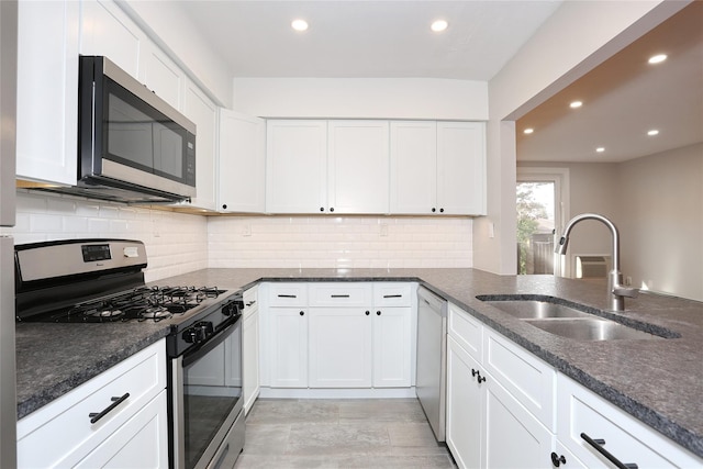 kitchen with backsplash, stainless steel appliances, sink, white cabinets, and light hardwood / wood-style floors