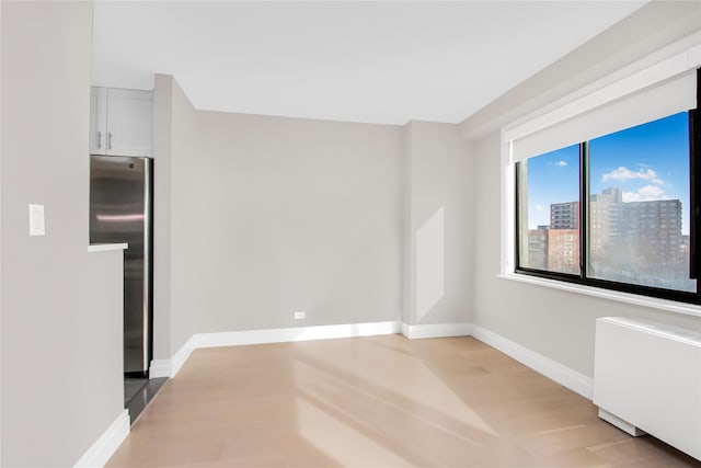 spare room with light wood-type flooring and radiator heating unit