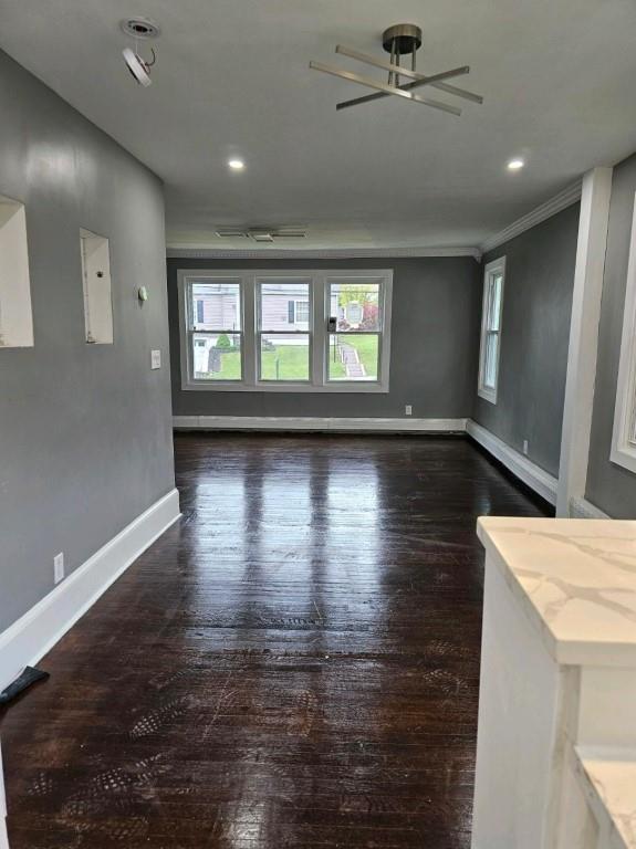 unfurnished living room with ornamental molding, dark hardwood / wood-style flooring, ceiling fan, and a baseboard heating unit