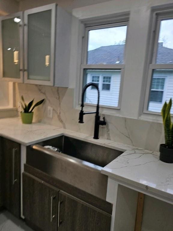 kitchen featuring light stone countertops, decorative backsplash, plenty of natural light, and sink