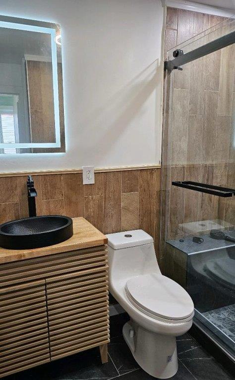 bathroom with tiled shower, vanity, and toilet