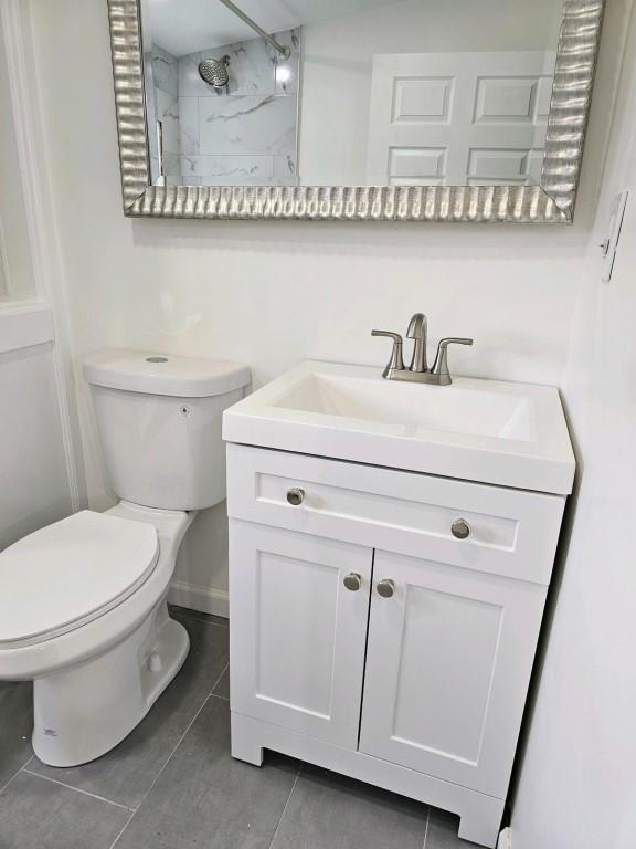 bathroom featuring toilet, a tile shower, vanity, and tile patterned floors