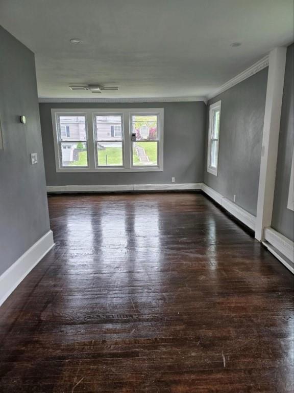 empty room with dark hardwood / wood-style flooring and ornamental molding