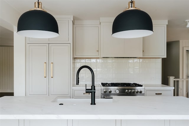 kitchen featuring white cabinets, light stone counters, high end range, and tasteful backsplash