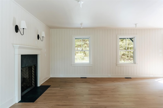 unfurnished living room with hardwood / wood-style flooring, crown molding, and wood walls