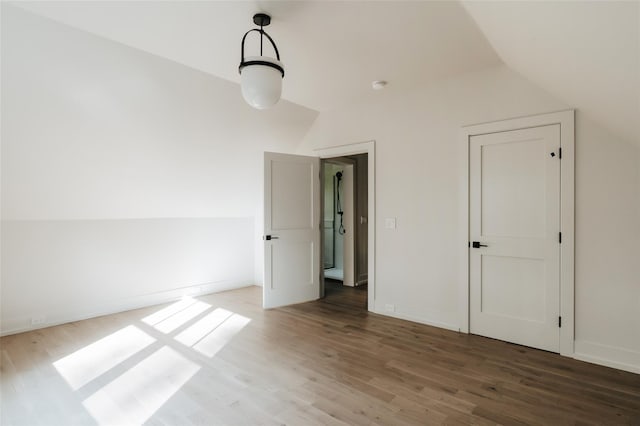 unfurnished bedroom with wood-type flooring and vaulted ceiling