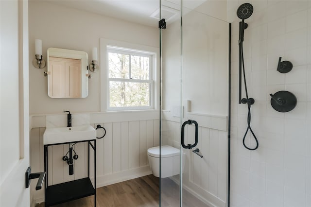 bathroom with hardwood / wood-style flooring, toilet, a shower with door, and sink