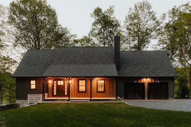 back of house featuring a lawn, a garage, and covered porch