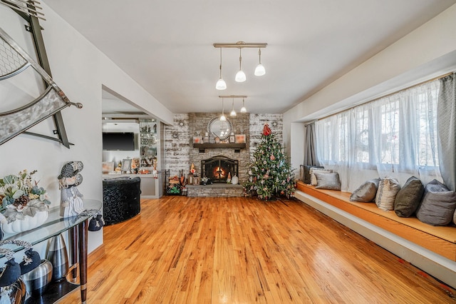 living room featuring a stone fireplace, brick wall, and hardwood / wood-style flooring