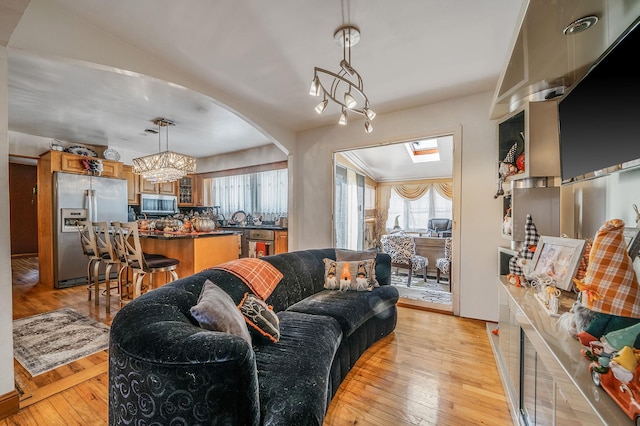 living room featuring a skylight, light hardwood / wood-style flooring, and a chandelier