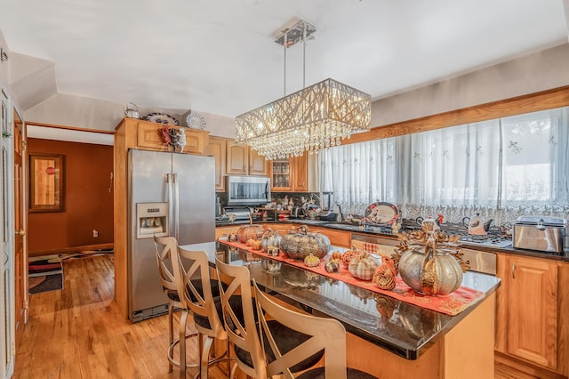 kitchen with light wood-type flooring, appliances with stainless steel finishes, decorative light fixtures, a kitchen island, and a chandelier