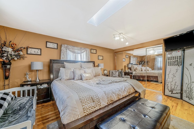 bedroom with a skylight, a closet, a chandelier, and hardwood / wood-style flooring