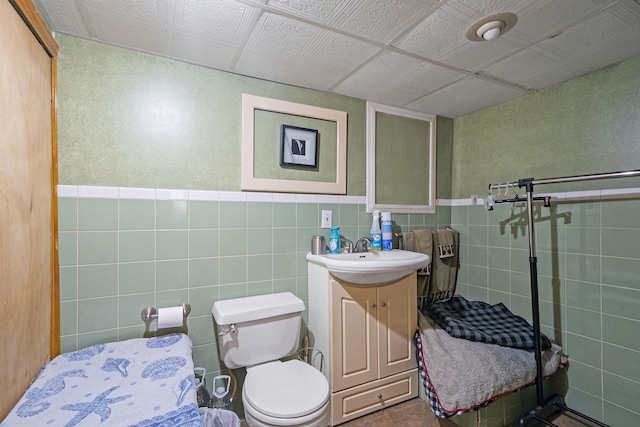 bathroom with vanity, toilet, and tile walls