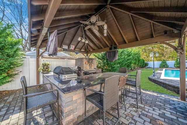 view of patio featuring grilling area, an outdoor bar, a gazebo, ceiling fan, and area for grilling