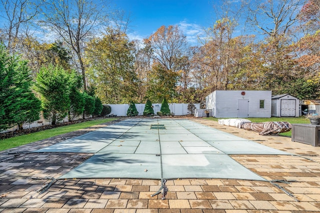 view of swimming pool featuring a patio area and a storage shed