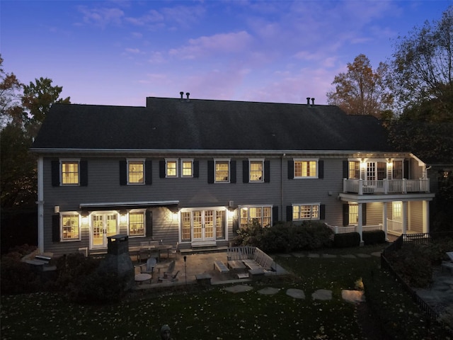 back house at dusk with a patio and a balcony