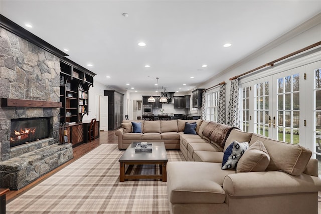 living room with a fireplace, light hardwood / wood-style floors, french doors, and ornamental molding