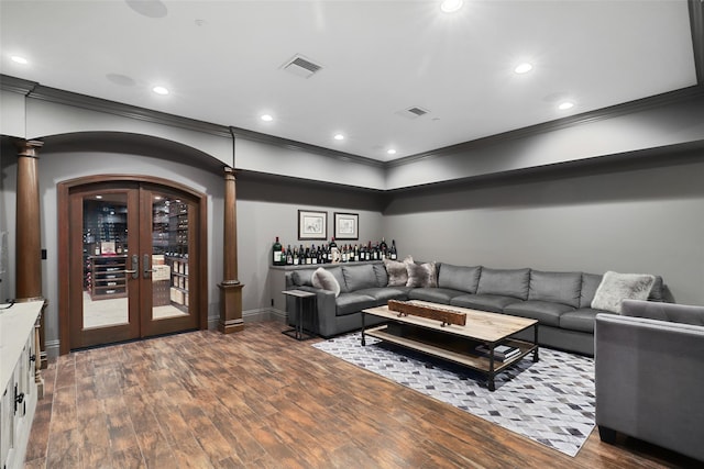 living room with french doors, ornate columns, ornamental molding, and dark wood-type flooring