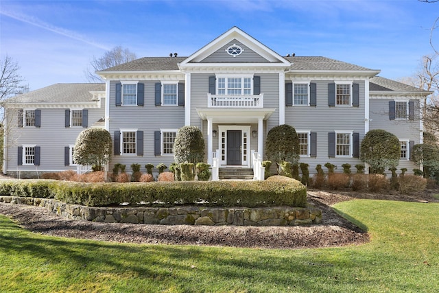 view of front of property featuring a balcony and a front yard