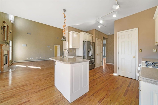 kitchen with white cabinets, sink, stainless steel refrigerator with ice dispenser, light hardwood / wood-style flooring, and decorative light fixtures