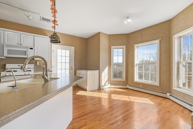 kitchen featuring white appliances, sink, decorative light fixtures, light hardwood / wood-style floors, and white cabinetry