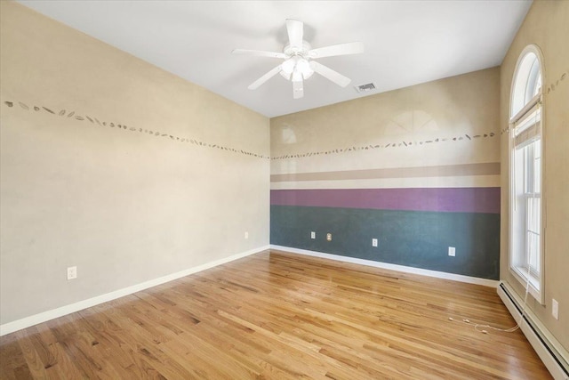 spare room with hardwood / wood-style floors, baseboard heating, and ceiling fan