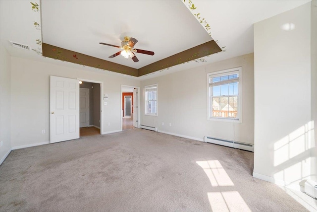 unfurnished bedroom with light carpet, a tray ceiling, and a baseboard heating unit