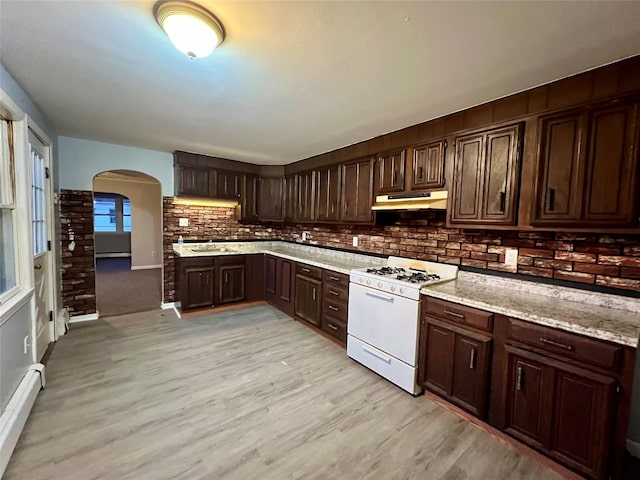 kitchen featuring decorative backsplash, dark brown cabinets, white range with gas cooktop, a baseboard radiator, and light hardwood / wood-style flooring