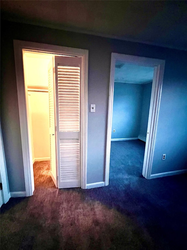 unfurnished bedroom featuring dark carpet and a closet