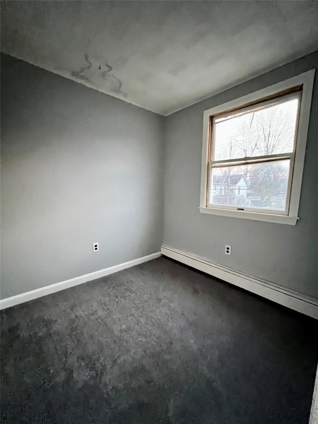 carpeted spare room with a textured ceiling and a baseboard radiator