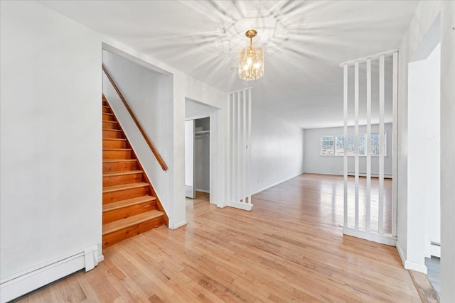 empty room with a chandelier, light hardwood / wood-style flooring, and a baseboard heating unit