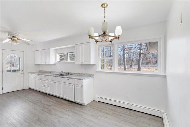 kitchen featuring ceiling fan with notable chandelier, a baseboard heating unit, white cabinets, light hardwood / wood-style floors, and hanging light fixtures