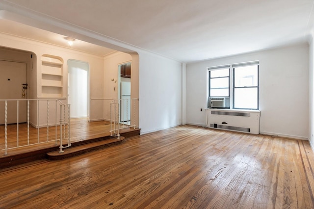 unfurnished living room featuring radiator heating unit, hardwood / wood-style flooring, and crown molding