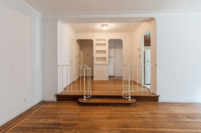 corridor with wood-type flooring and ornamental molding