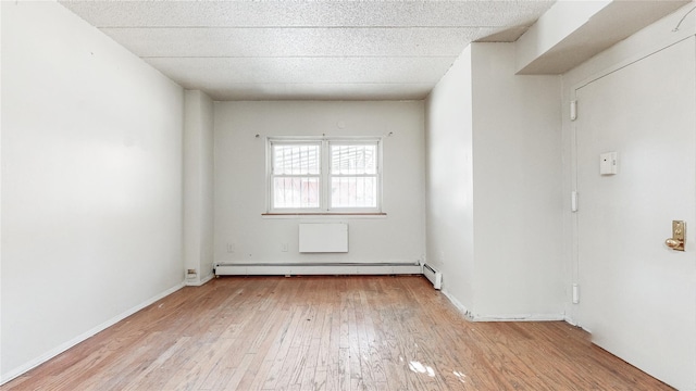 unfurnished room with a paneled ceiling, light hardwood / wood-style floors, and a baseboard heating unit