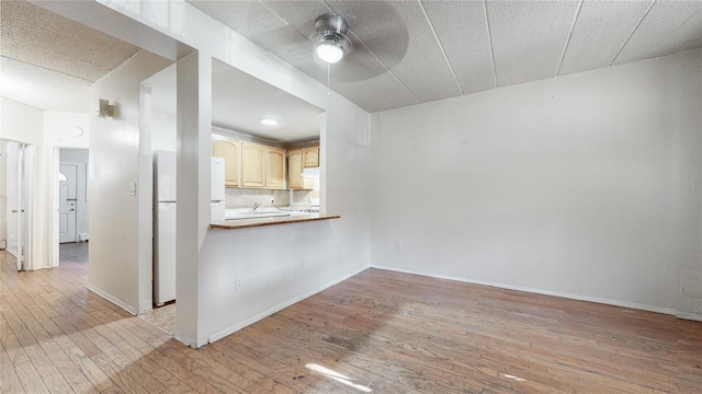 interior space featuring ceiling fan, white refrigerator, light wood-type flooring, and kitchen peninsula