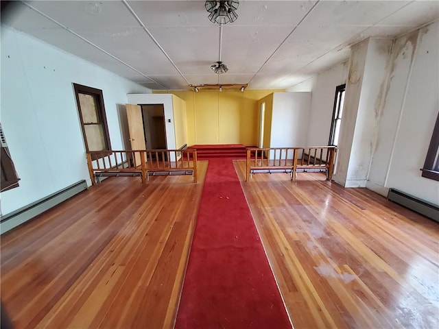 empty room featuring wood-type flooring and a baseboard radiator