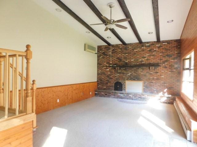 unfurnished living room with a wall mounted air conditioner, a baseboard heating unit, wooden walls, ceiling fan, and beamed ceiling