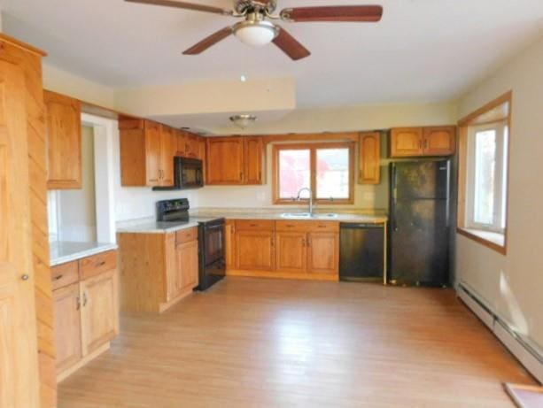 kitchen with ceiling fan, sink, a baseboard radiator, light hardwood / wood-style flooring, and black appliances