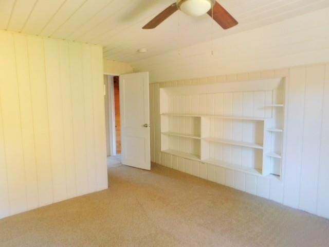 spare room featuring ceiling fan, carpet floors, and wooden walls