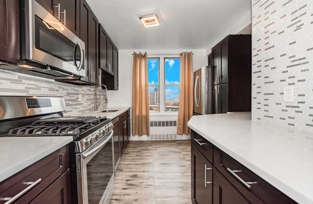 kitchen featuring dark brown cabinets, backsplash, stainless steel appliances, and sink