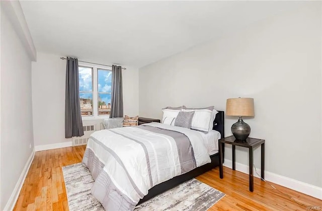 bedroom with wood-type flooring and radiator heating unit